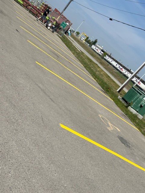 A Crax professional meticulously applying vibrant, durable line paint on a parking lot in Calgary, demonstrating our commitment to precision and quality in line painting services.